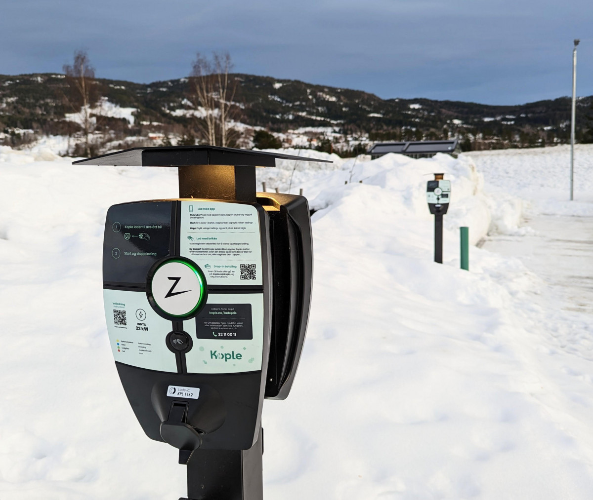 Elbillader på parkeringsplass i vinterføre